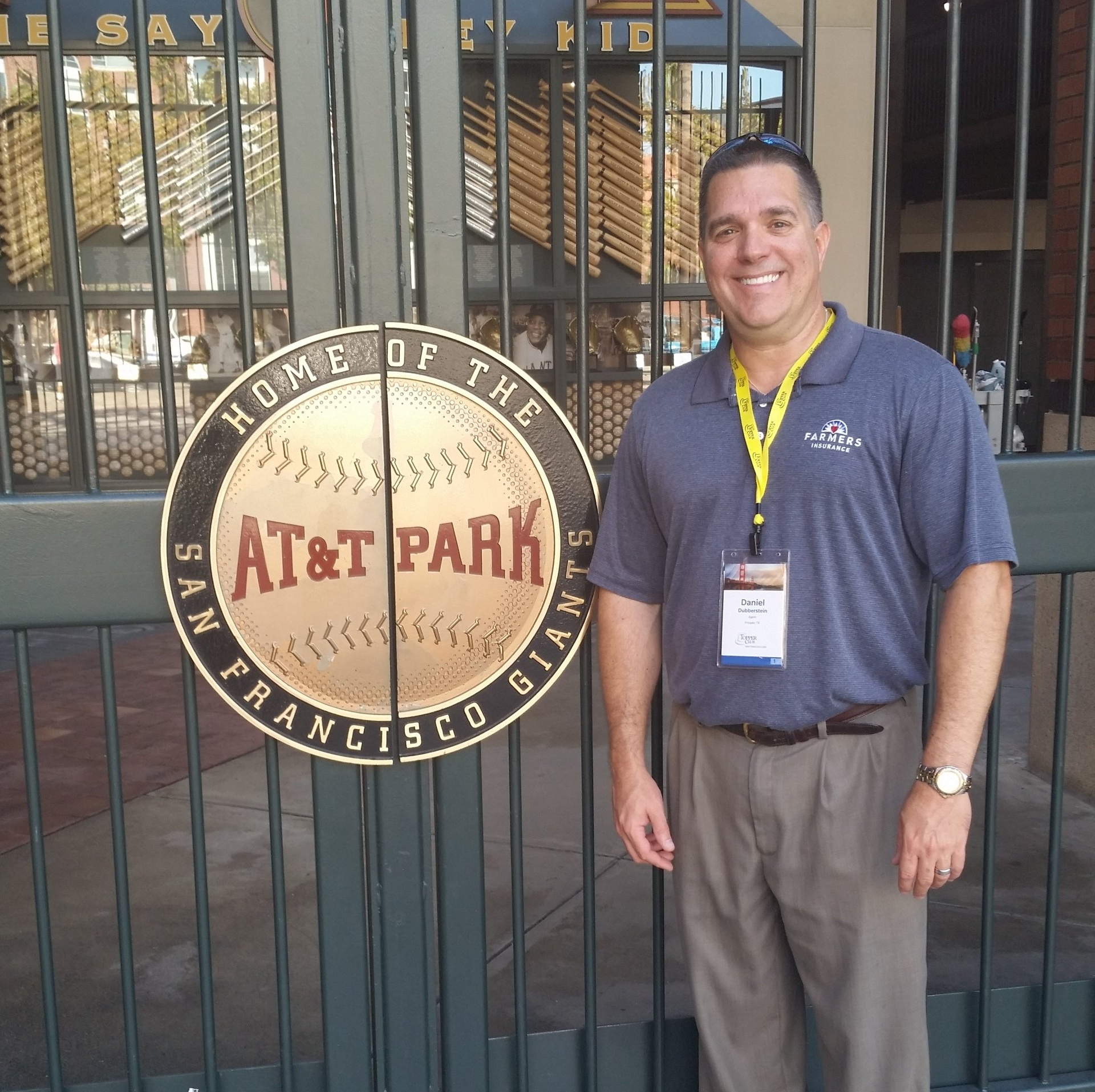 Man standing by the AT&T Park gate sign in San Francisco, wearing a gray polo and lanyard.